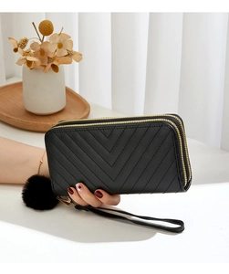 Detail of black chevron quilted long wallet with double zippers, wristlet and pompom charm