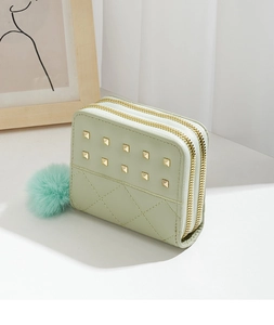 Détail du mini portefeuille vert clair avec clous, double fermeture et pompon doux