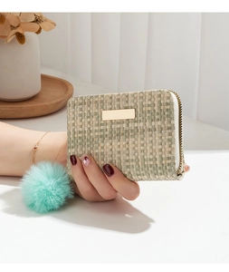 Detail of woven wallet with gold metal plate and mint green fur ball keychain