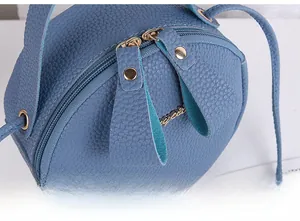 Detail of smooth double zipper and lychee pattern leather on dark blue round handbag