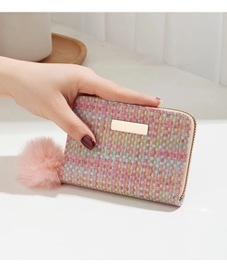 Detailed texture of pink woven tweed small wallet with gold metal plate and pompom charm