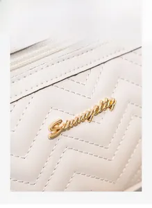 Détail du sac en similicuir blanc matelassé avec logo métallique doré élégant