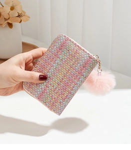 Close-up of colorful woven card holder featuring a pink plush pompom keychain accessory