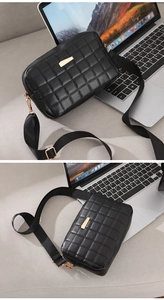 Detail of black quilted crossbody bag featuring gold buckle and wide fabric shoulder strap