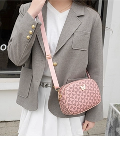 Vue détaillée du sac bandoulière rose avec motif géométrique et accessoire papillon doré