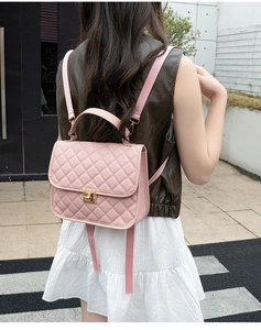 Detailed view of pink quilted leather backpack with gold twist lock on female model