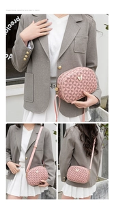 Sac bandoulière rose avec motif géométrique et logo papillon doré porté par modèle