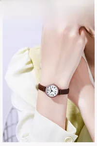 Primo piano dell'orologio retrò da donna con sottile cinturino in pelle marrone