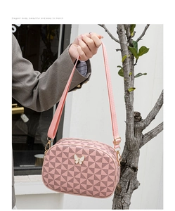 Vue détaillée du sac bandoulière rose à motif géométrique et boucle papillon en métal