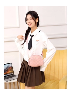 Detail of pink quilted messenger bag with gold logo and wide shoulder strap
