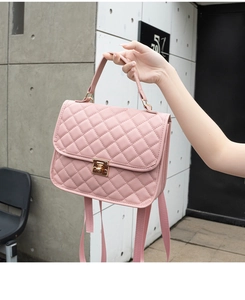 Detail of pink quilted handbag with gold metal twist lock and wide fabric shoulder strap