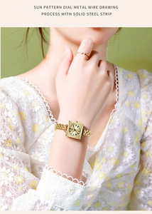 Close-up of gold square watch with sunray dial and solid steel strap worn by a model