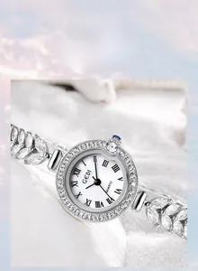 Macro detail of silver wheat-shaped watch bracelet with cubic zirconia and blue gem crown