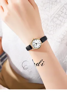 Détail d'une montre vintage en or avec chiffres romains et bracelet en cuir de serpent noir