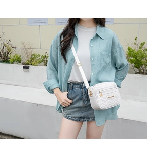 Détail du sac bandoulière blanc avec matelassage en V et ferrures dorées à double zip