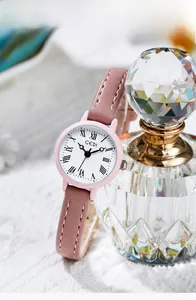 Primo piano di un orologio al quarzo rosa con numeri romani accanto a una boccetta