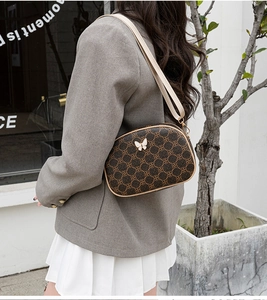 Détail du sac à bandoulière vintage à motif avec ornement papillon porté par un mannequin