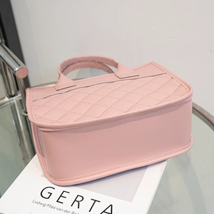 Sac fourre-tout rose élégant avec coutures en losanges sur un bureau en verre