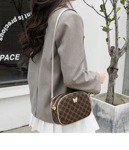 Sac bandoulière vintage marron à motif floral avec papillon porté par un mannequin