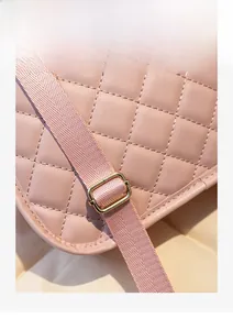 Close-up of pink quilted backpack with adjustable woven strap and gold buckle hardware