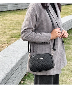 Détail d'un sac caméra noir matelassé avec logo doré et bandoulière réglable