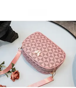 Détail du sac bandoulière rose à motif géométrique avec charm papillon et boucles dorées