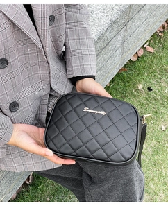 Détail du sac photo matelassé noir avec un logo élégant en métal doré sur le devant