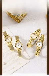 Close-up of golden quartz watches with Milanese mesh and metal chain straps on white fabric
