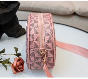 Sac bandoulière rose avec imprimé géométrique et sangle tissée sur une surface blanche