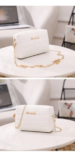Close-up of white quilted chain bag with gold cursive logo and elegant marble background