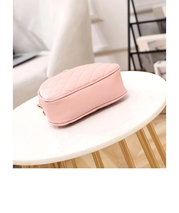 Detail of light pink quilted crossbody bag on marble table with gold hardware accent