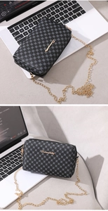Close-up of black embroidered chain bag with geometric pattern and golden logo
