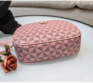 Détail d'un sac à bandoulière rose avec imprimé géométrique et ornement papillon