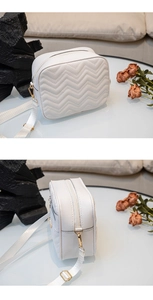 Détail du sac bandoulière blanc avec motif matelassé en V et finitions dorées chic