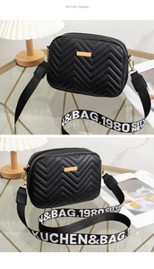 Detail of black quilted crossbody bag with golden plaque and stylish woven strap
