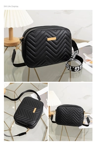 Detail of black chevron quilted crossbody bag with gold metal plaque and woven strap