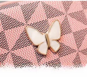 Détail du motif géométrique rose et de la boucle en métal en forme de papillon blanc