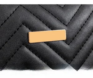 Close-up of elegant V-quilted black leather bag with a luxury gold metal buckle detail