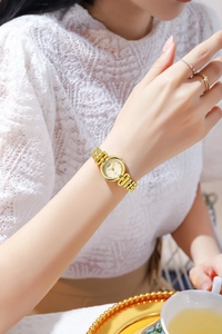 Elegant gold quartz watch for women with textured round dial on a model's wrist