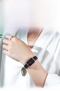 Fashionable square rose gold watch with black leather strap worn on female wrist