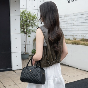 Grande borsa a mano trapuntata nera con logo a fiore dorato su outfit chic