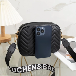 Black chevron quilted crossbody camera bag with wide logo woven strap and compact size