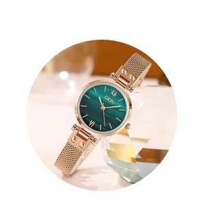 Close-up of rose gold mesh strap watch with deep green sunburst dial and roman numerals