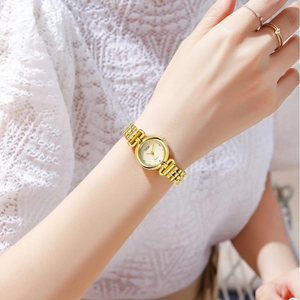 Elegant gold quartz watch for women with textured metal strap worn on wrist