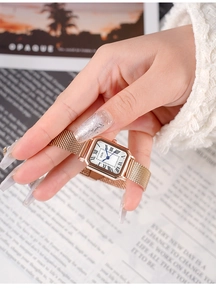 Close-up of a vintage rose gold rectangular quartz watch with a Milanese steel strap