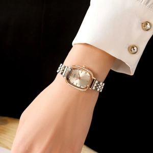 Montre femme ovale élégante avec lunette en strass et bracelet en acier bicolore