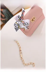 Detail of pink crossbody bag with silk scarf bow and detachable gold chain strap