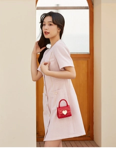 Detail of red heart mini bag with gold chain over a pink tweed short sleeve dress