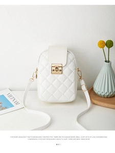 Detail view of a white quilted phone crossbody bag with a golden rectangular metal lock