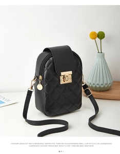 Detail of black quilted crossbody phone bag featuring a gold clasp and thin strap